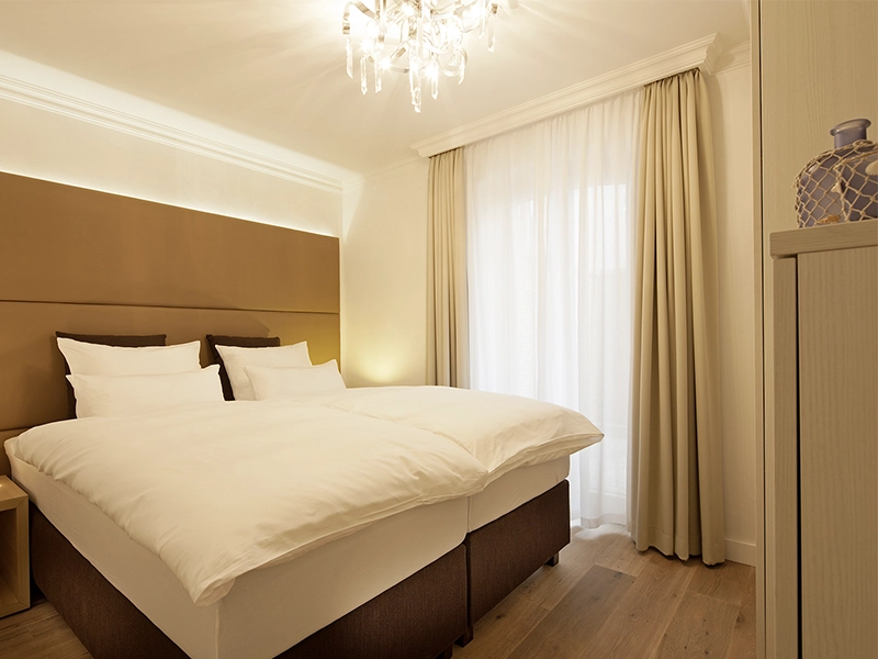Blick in das Apartment Maison N°1 der Villa Vie auf Norderney. Zu sehen ist das Schlafzimmer mit frisch bezogenem und gemütlichem Doppelbett.