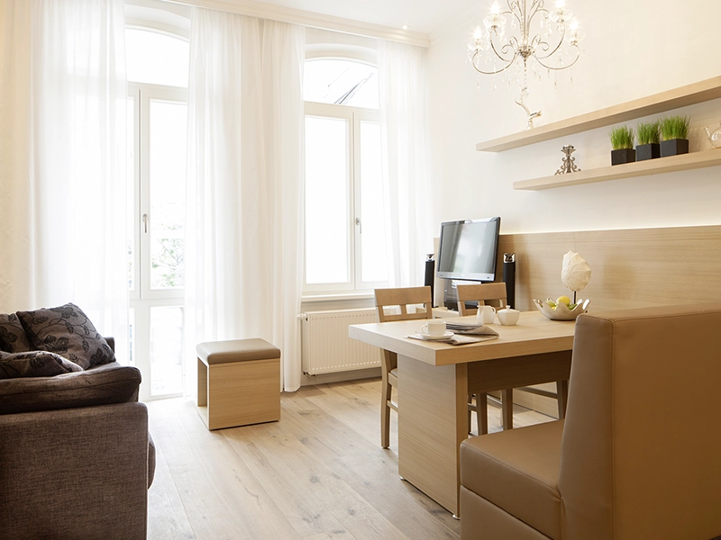 Blick in das Apartment Maison N°1 der Villa Vie auf Norderney. Zu sehen ist die Ess- und Wohnecke mit Esstisch, Couch und TV.