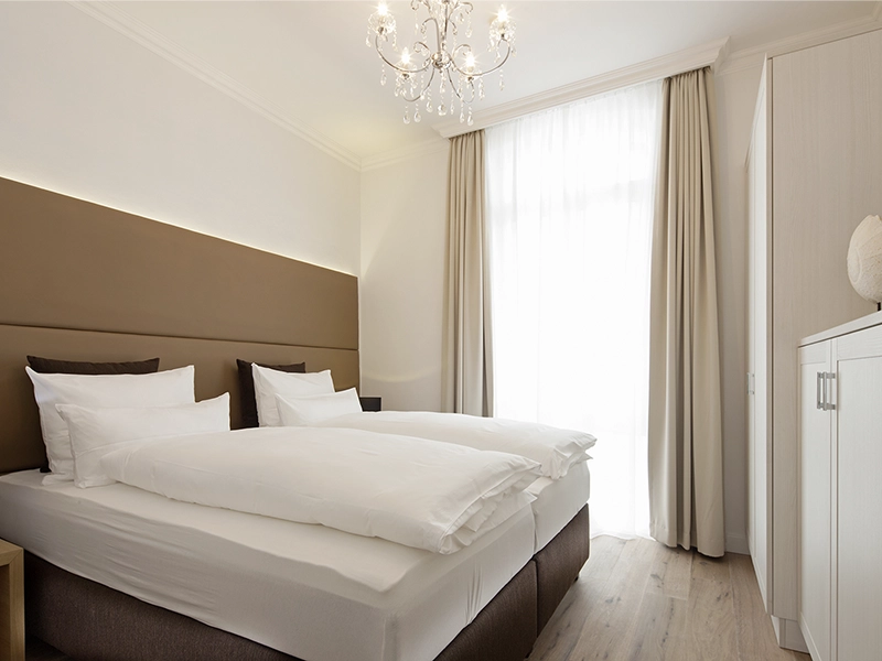Blick in das Apartment Maison N°3 der Villa Vie auf Norderney. Zu sehen ist ein Schlafzimmer mit gemütlichem Doppelbett darin.