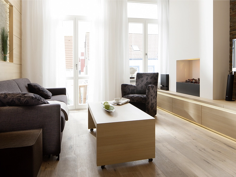 Blick in das Apartment Maison N°3 der Villa Vie auf Norderney. Zu sehen ist der Wohnbereich mit Couch und Sitzgelegenheit.