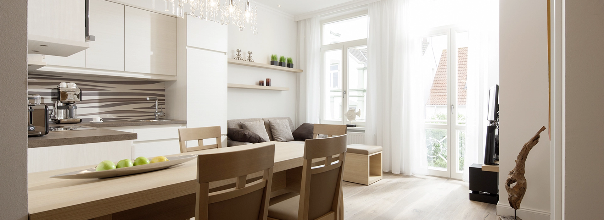Blick in das Apartment Maison N° 4 der Villa Vie auf Norderney. Zu sehen ist der Esstisch, die Küche und die bequeme Sitzecke.