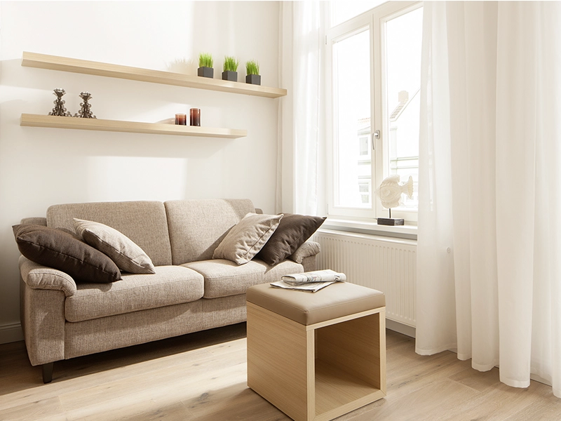 Blick in das Apartment Maison N°4 der Villa Vie auf Norderney. Zu sehen ist eine gemütlich Sitzecke mit Couch und Beistelltisch.