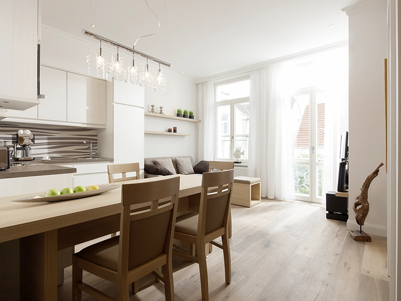Blick in das Apartment Maison N° 4 der Villa Vie auf Norderney. Zu sehen ist der Esstisch, die Küche und die Sitzecke.