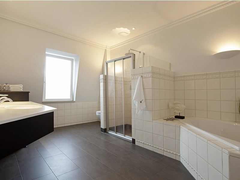 Blick in das Apartment Maison Penthouse N° 5 der Villa Vie auf Norderney. Zu sehen ist das große und luxuriöse Badezimmer mit Badewanne, Dusche und zwei Waschbecken.