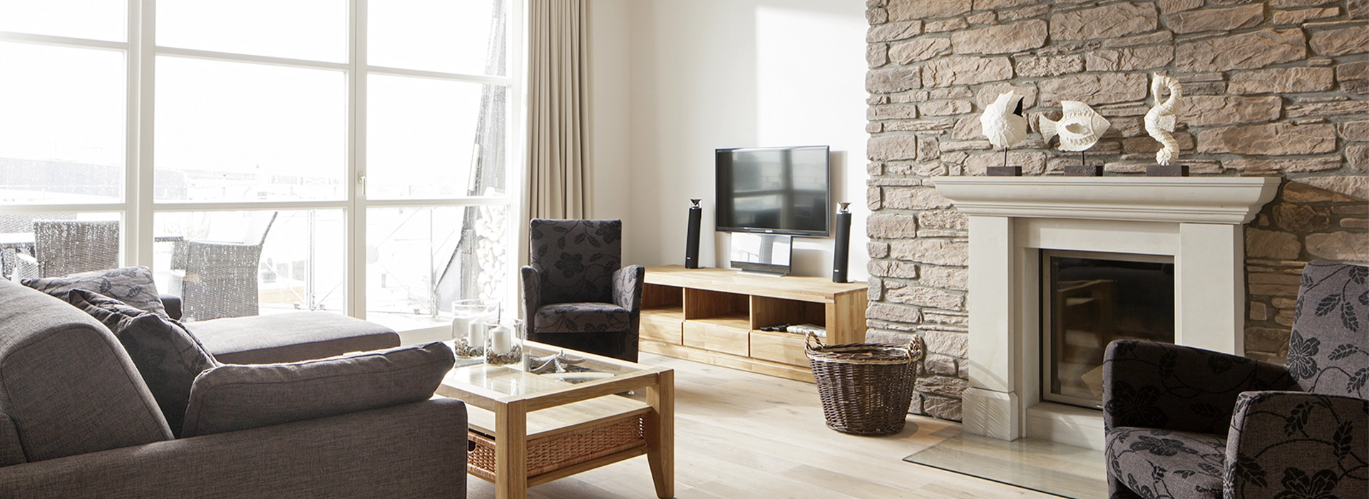 Blick in das Apartment Maison Penthouse N° 5 der Villa Vie auf Norderney. Zu sehen ist der Wohnbereich mit TV und Kamin.