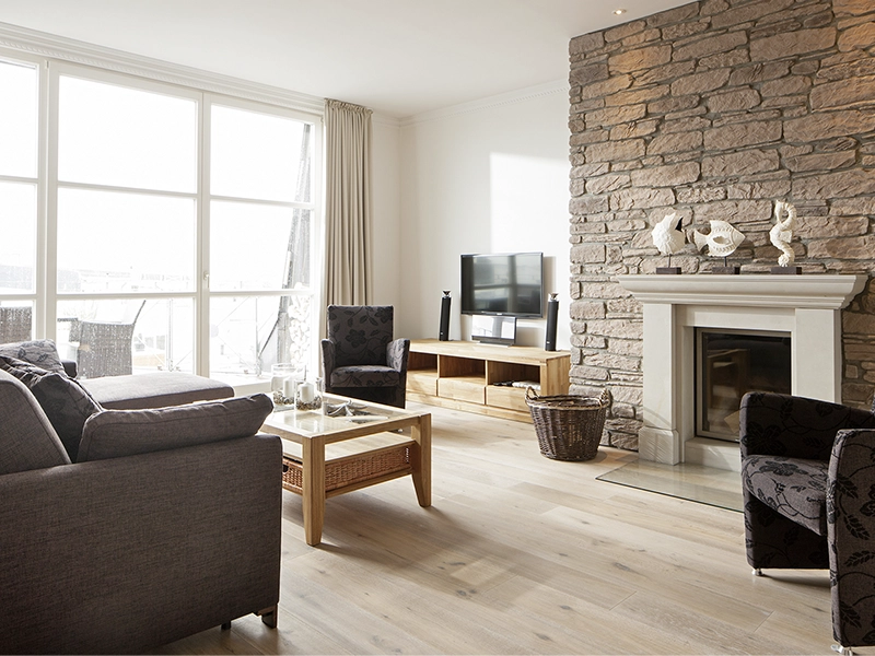 Blick in das Apartment Maison Penthouse N°5 der Villa Vie auf Norderney. Zu sehen ist der Wohnbereich mit einer entspannten Sitzecke und mit Fokus auf den Kamin.