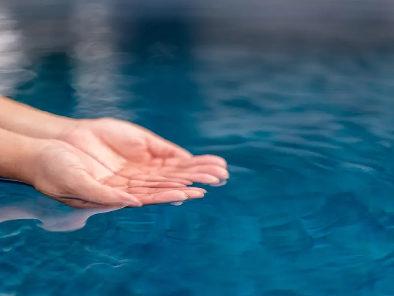 Eine Hand in einem Pool, die Wasser auffängt und hält.