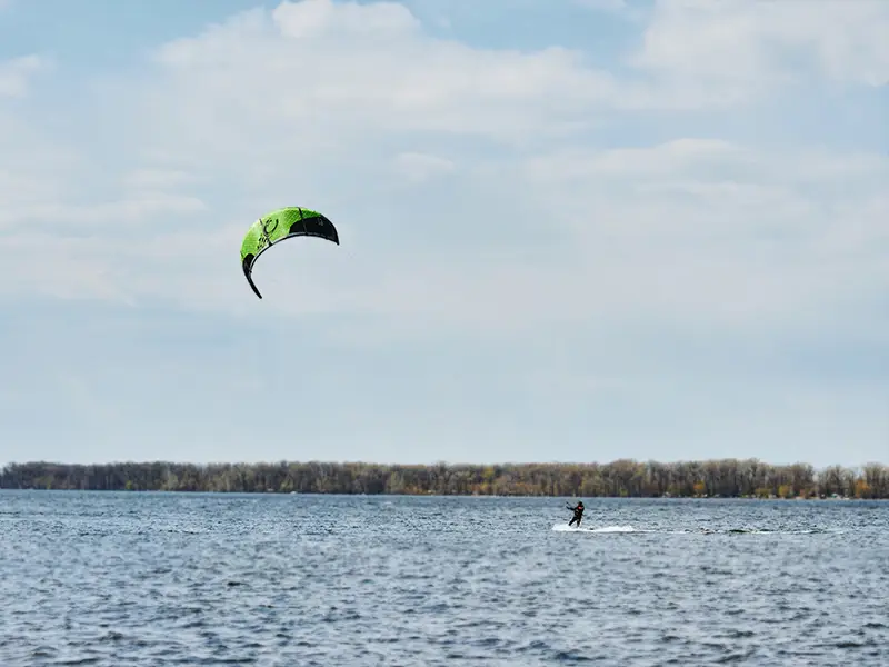 Zu sehen ist ein Kitesurfer in der Ferne auf den Gewässern der Norderney bei windigem Wetter.