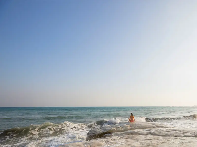Zu sehen ist eine Frau am Strand, entspannt, in Vorbereitung auf eine Thalasso Kur am Strand auf Norderney.