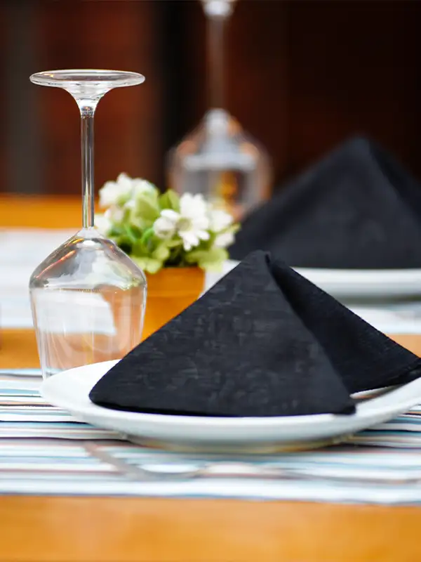 Ein edler gedeckter Tisch in einem Restaurant mit Serviette und Weinglas fertig auf dem Tisch.