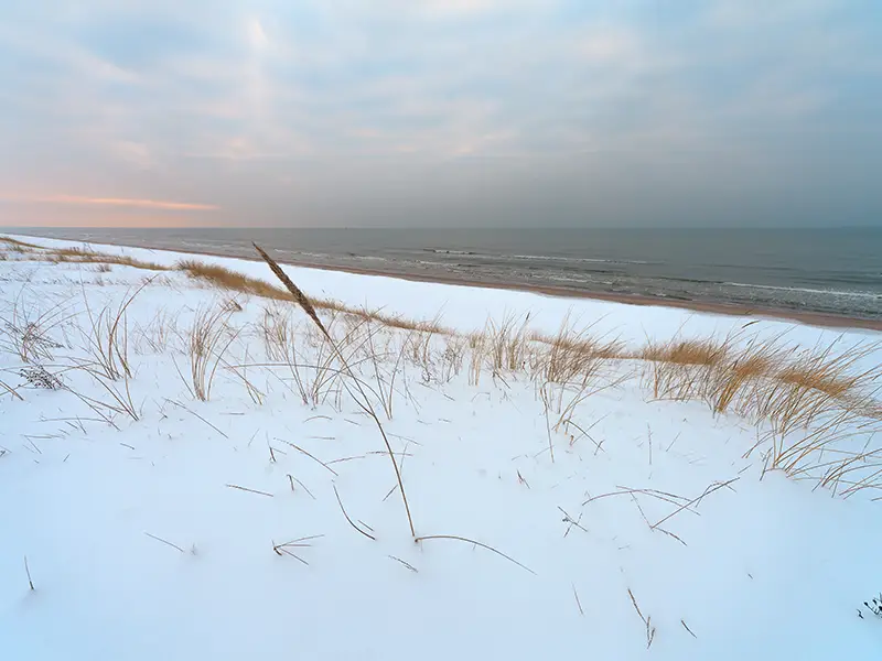 Zu sehen ist die verschneite Strandlandschaft der Norderney im Winter.