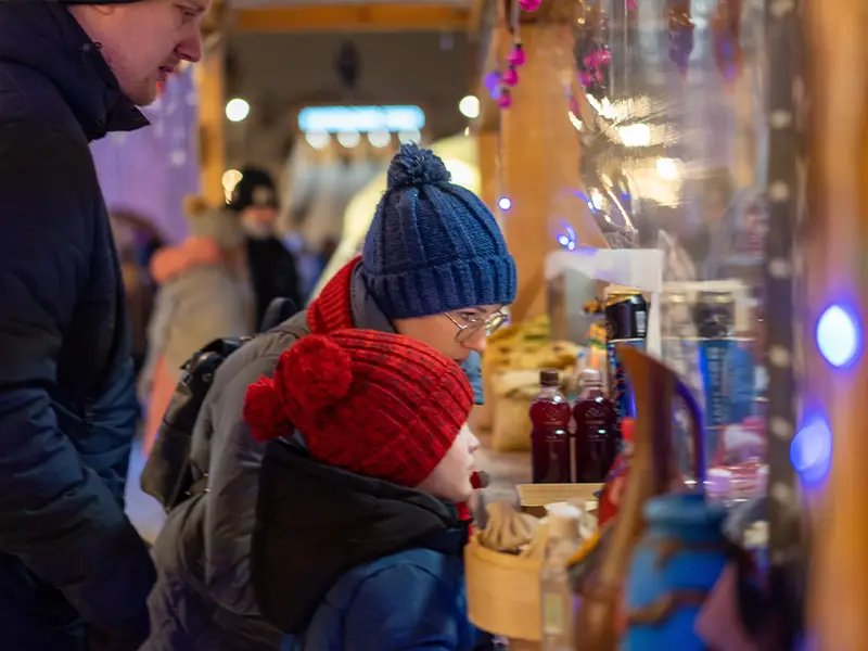 Zu sehen ist ist eine Familie, die sich auf dem Winterzauber Weihnachtsmarkt auf der Norderney die Stände anguckt.