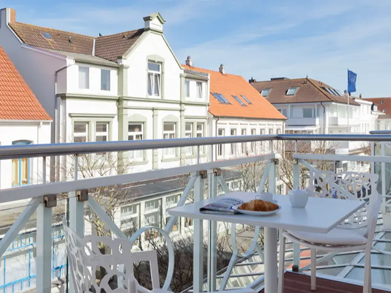 Zu sehen ist der Ausblick aus einem Apartment der Villa Vie mit gedecktem Frühstückstisch und Sonne im Hintergrund.