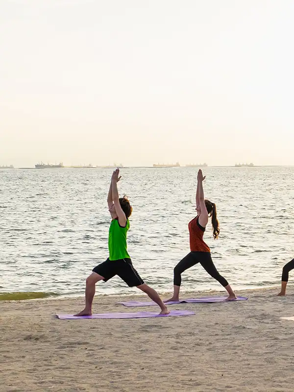 Ein Gruppe Menschen, die Yoga am Strand beim Sonnenuntergang machen.