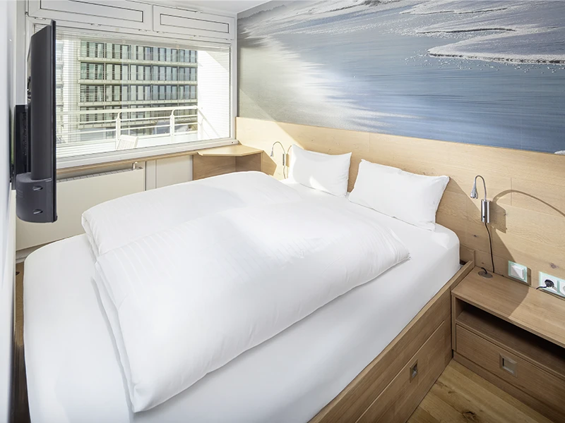 Schlafzimmer im Apartment Nordseeblick mit Doppelbett, Nachttischen und großem Fenster