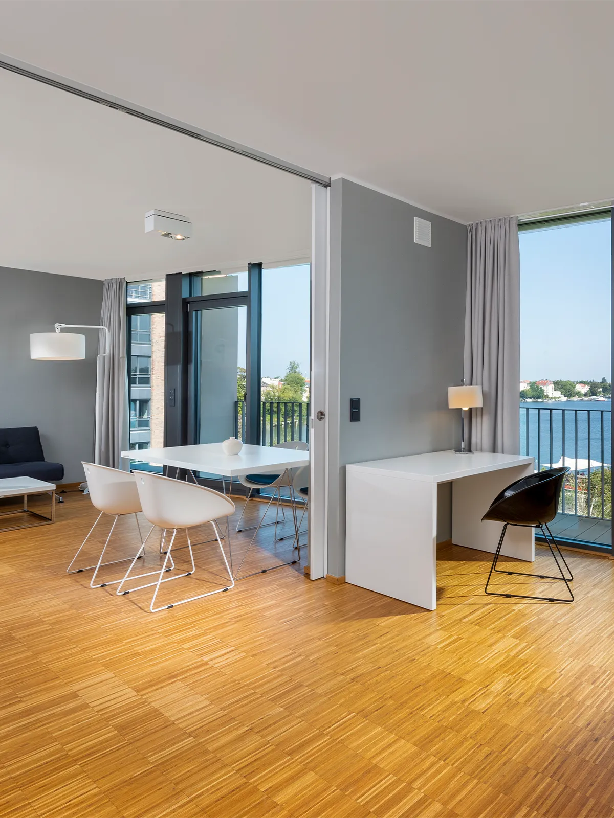 Helles Apartment im WAVE Hotel Potsdam mit Essbereich, Arbeitsnische, modernem Interieur und bodentiefen Fenstern mit Blick auf die Havel.